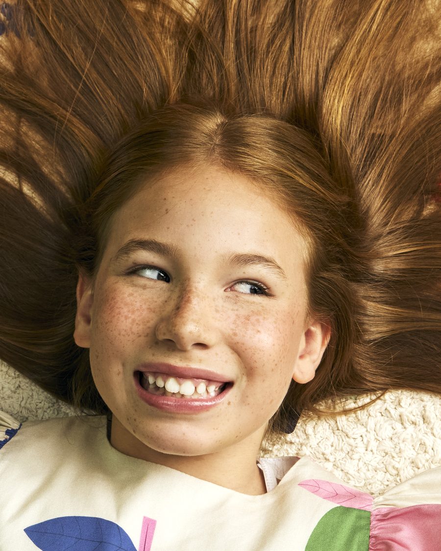 Menina deitada, sorrindo, com o cabelo espalhado ao redor do rosto