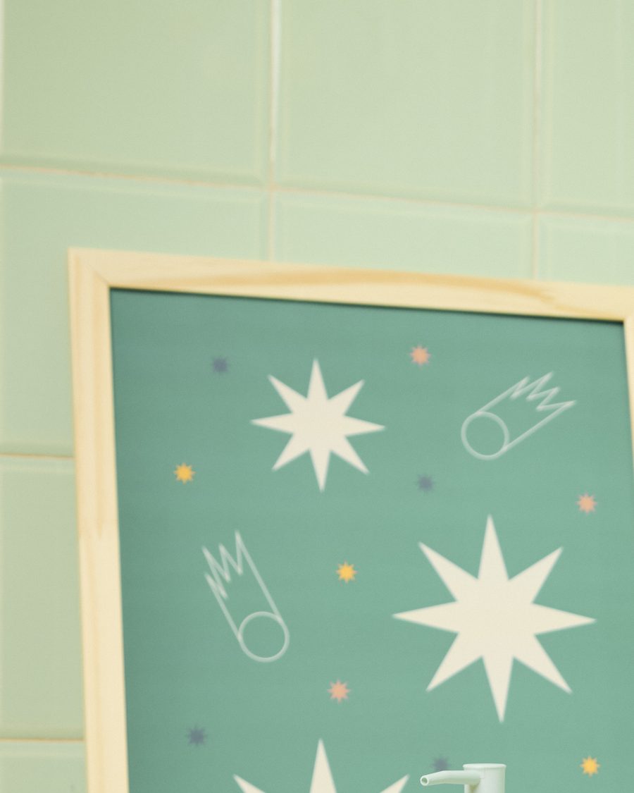 Quadro com estrelas sobre a parede de azulejo verde do banheiro